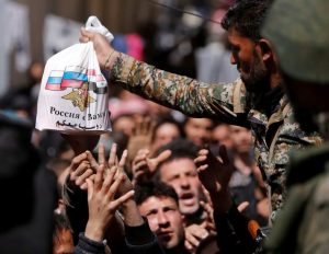 A Syrian army soldier distributes aid from Russian forces to civilians-Milenio Stadium-Canada