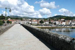 There are more than enough reasons to visit the oldest Portuguese town. Choose from its museums or rich history and don’t forget the local cuisine and the lagoons just outside Ponte de Lima. Besides, this town is also one of the best stops for a rest day if you’re walking the Portuguese Central Camino de Santiago. The most iconic image of lovely Ponte de Lima is, without a doubt, that of the bridge over the river Lima with the 18th century church of Santo António da Torre Velha and the Guardian Angel Chapel on the side opposite to the town centre. The bridge, both Roman and medieval, crosses the river Lima, the main character in a legend dating back to Roman times and which tells the story of a group of soldiers who were too scared to cross the river. They believed the Lima was in fact the Lethe, the river of forgetfulness in Greek mythology, and crossing it meant forgetting everything, including their family and their homeland. The consul decided to cross the river alone to convince them they were wrong and, having reached the other margin, called the soldiers one by one, proving them the Lima was not the Lethe. The mock Roman troops made of wood that you’ll find near the bridge act as a reminder of this legend. Interested in exploring the art of azulejo, Portuguese painted tiles? In Ponte de Lima you’ll find several tile panels, both traditional and modern, illustrating scenes of legend and history, landscapes and even poems. You can take the Rota dos Azulejos (Tile Route) pedestrian route to make sure you don’t miss a single one. After a stroll along the river bank, make a little time for a drink and a snack in Largo do Camões, the central plaza that provides the perfect backdrop to relax and watch life go by. While in the historical part of Ponte de Lima don’t forget to visit the Gothic church (Igreja Matriz), the 14th century prison tower (Torre da Cadeia Velha) and the 17th century fountain. The Center for the Interpretation of the Territory (Centro de Interpretação do Território) is also worth visiting to become acquainted with objects that used to be part of the daily lives of the people in the region: from bread and wine making to folklore, weaving and the production of linen, among other areas. Also worthy of your time while in Ponte de Lima are the Museum of the Third Order (Museu dos Terceiros) and the Portuguese Toy Museum (Museu do Brinquedo Português): the first is the most important reference in terms of religious art in the north of Portugal, occupying both the former Convent of Santo António dos Capuchos and the building of the Third Order of Saint Francis; the latter takes you on an amazing journey through the world of toys made in Portugal, from the late 19th century until 1986. Maybe you’ll see some toys similar to those you had as a child, too! Not far from Ponte de Lima you’ll find a little gem of natural beauty: the Lagoons of Bertiandos and S. Pedro d’Arcos. The mix of Mediterranean, Atlantic and Continental climates in the area allows for the existence of lagoons, rivers, pastures and forests. These ecosystems provide the perfect conditions for the local fauna and flora and, in fact, this is the only classified wetland in the north of the country. The 9km long Lagoons Eco Trail (Ecovia das Lagoas) will take you from Ponte de Lima to this unique protected landscape. As one might expect, such an old and traditional town has its fair share of equally traditional and time-tested dishes. The most popular one is, without a doubt, arroz de sarrabulho, a rice dish prepared with different cuts of meat, spices and pig’s blood. Also starring on local menus you’ll find lamprey (from the river Lima), bacalhau (salted cod, which you can find all over Portugal), bísaro pork, traditional broa de milho (cornbread) and the sweet leite creme (creme brulee). How to wash it all down? With the local vinho verde, of course! Right in the heart of Ponte de Lima’s historical centre, the Vinho Verde Centre for Interpretation and Promotion (Centro de Interpretação e Promoção do Vinho Verde) supports and promotes not only vinho verde but also the whole region. The Centre hosts a permanent exhibition focusing on the history of vinho verde, its production, certification and endorsement, but there are also temporary exhibitions and, of course, a wine tasting room-portugal-mileniostadium