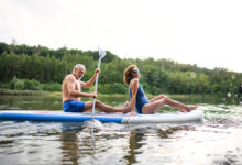 senior-couple-paddleboarding-on-lake-in-summer-2021-08-31-22-18-24-utc - milenio stadium