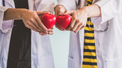 Two doctors holding red heart, health care concept.