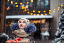 Portrait of joyful girl with a gift box for Christmas on a city