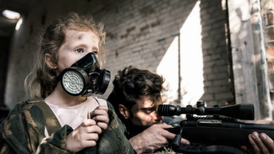 selective-focus-of-kid-in-gas-mask-near-man-with-g-2023-11-27-05-27-36-utc