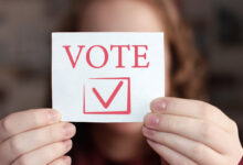 Vote sign in young woman's hands. Voting or making choice concept.