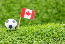 soccer-ball-with-flag-of-canada-on-green-grass-2023-11-27-05-07-23-utc